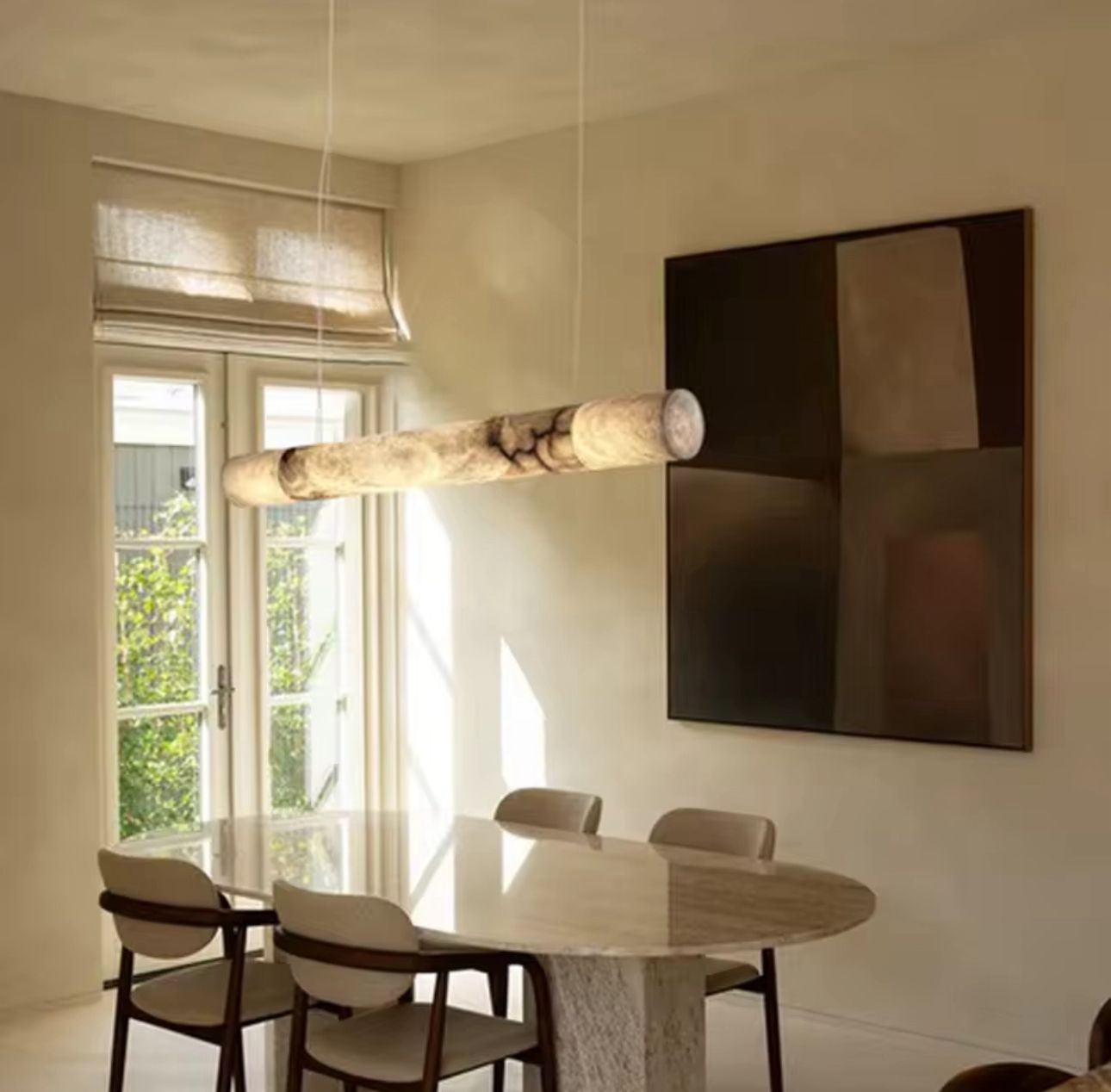 Cylindrical marble pendant light suspended above modern dining table