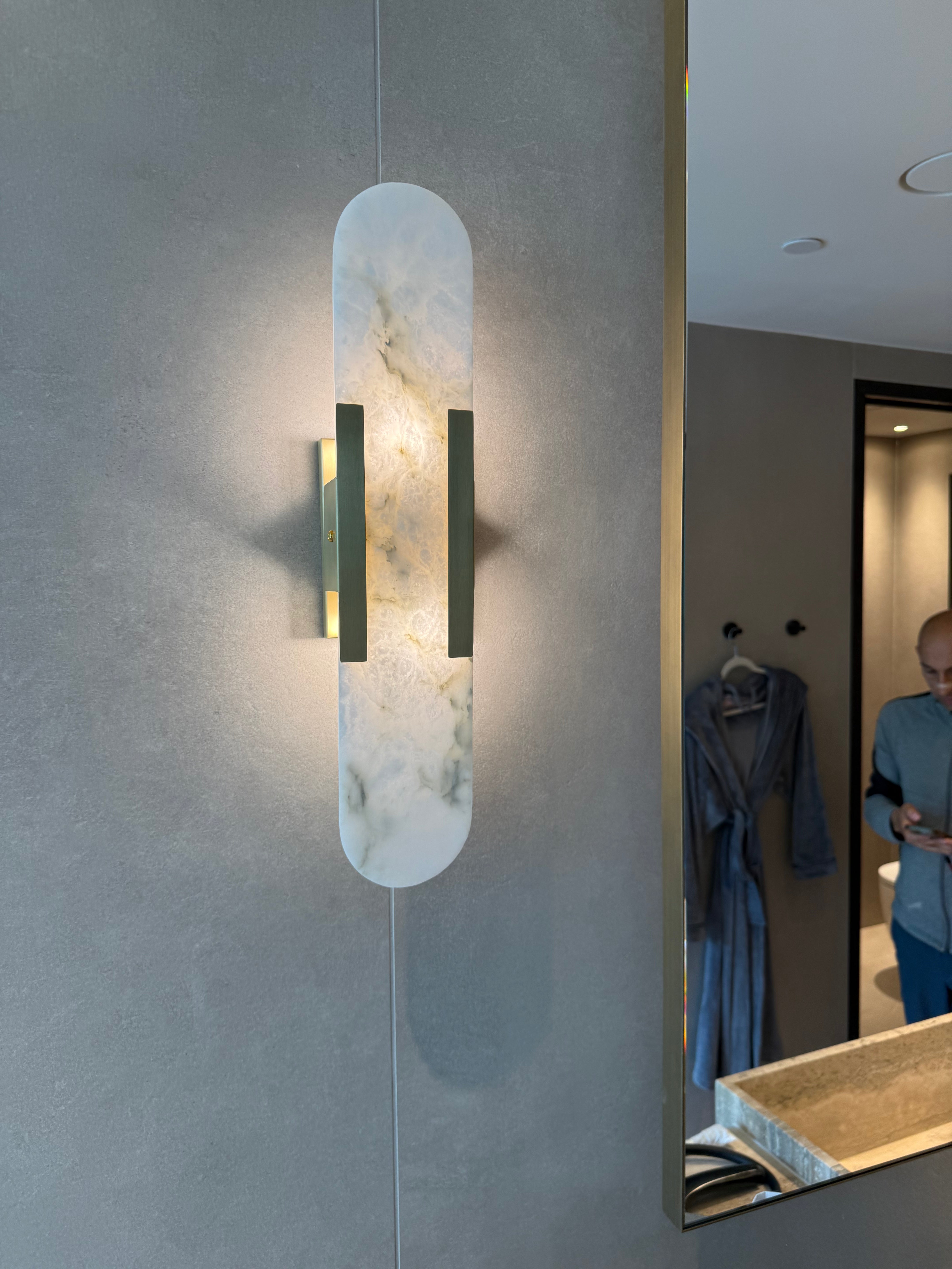 Modern wall sconce with marble-like finish in a bathroom setting