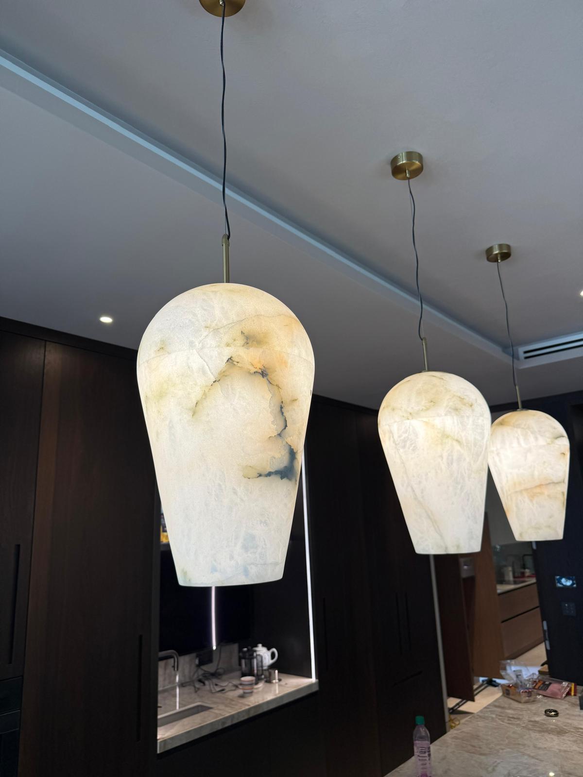 Three marble-textured pendant lights hanging in a modern kitchen.