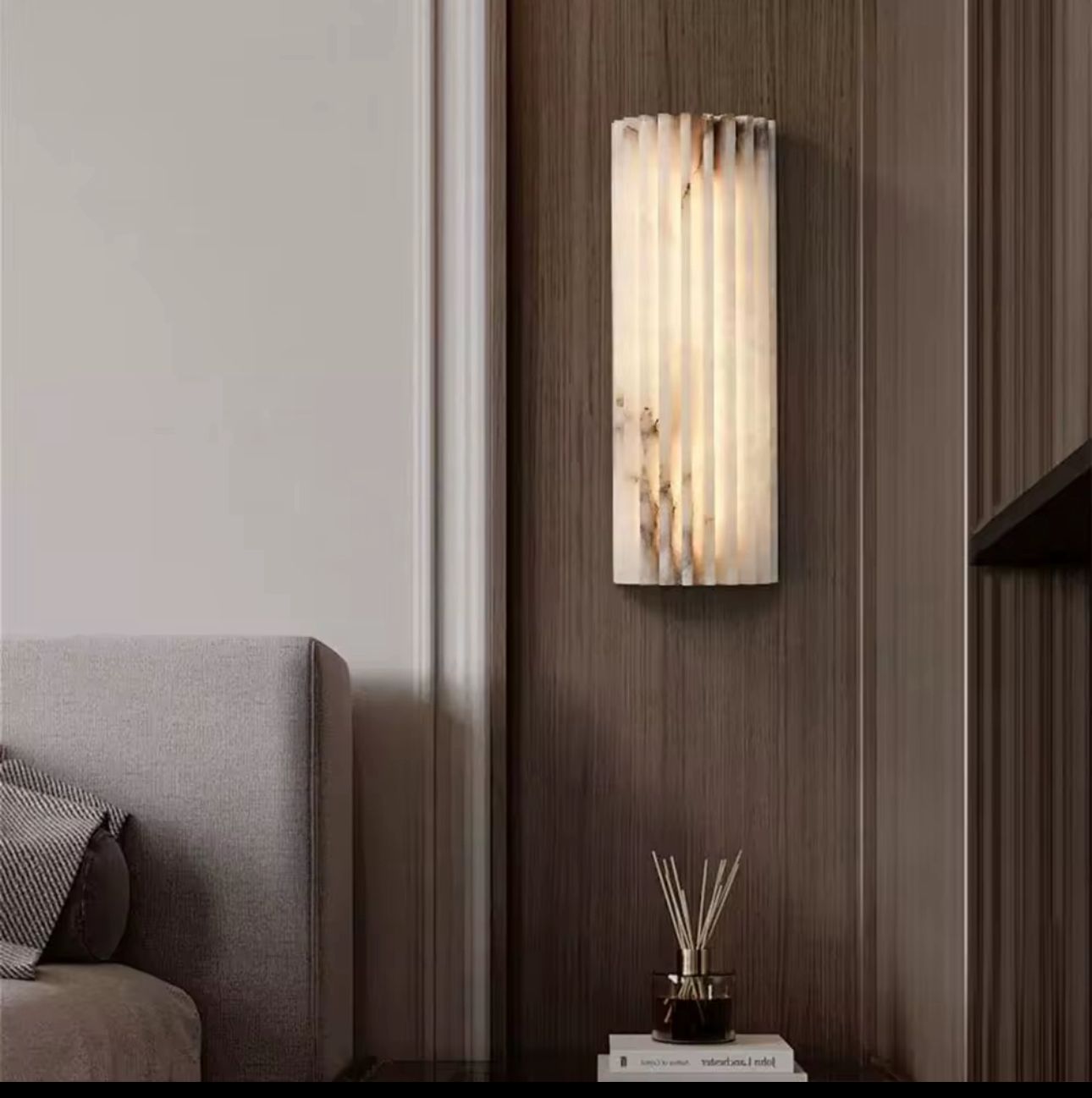 Wall-mounted light fixture on a wooden wall next to a gray sofa.