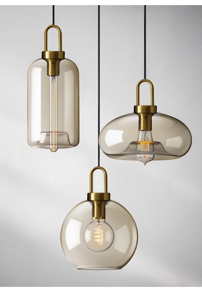 Three pendant lights with glass shades and brass fixtures on a neutral background