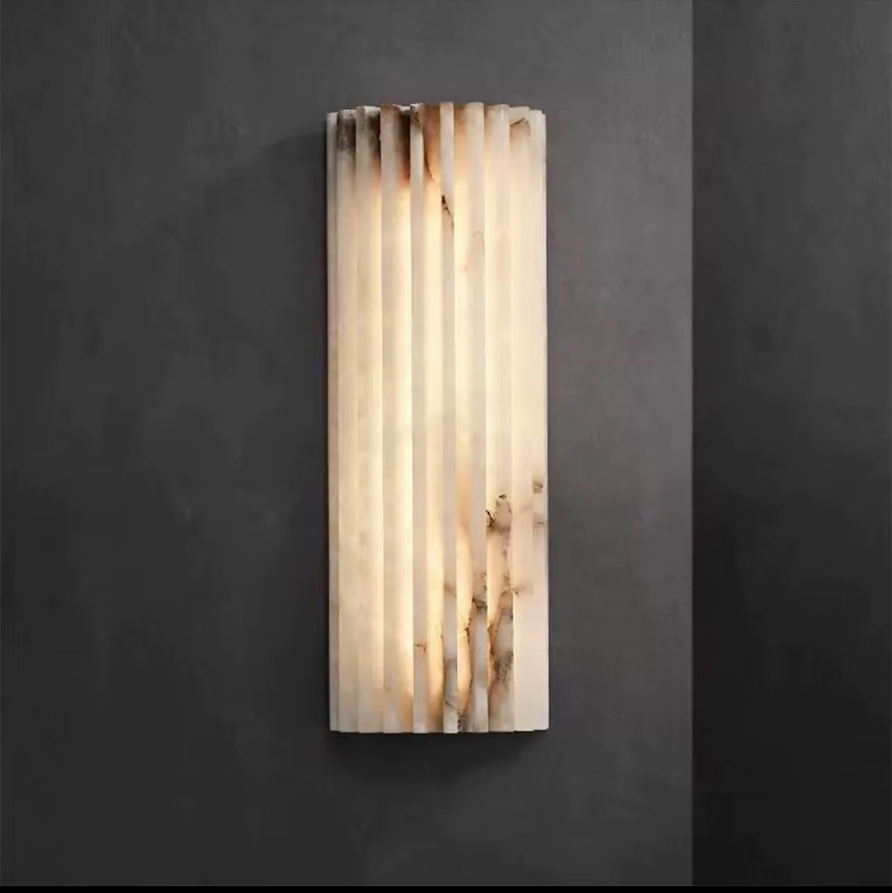 Decorative wall sconce with a ribbed design on a dark background
