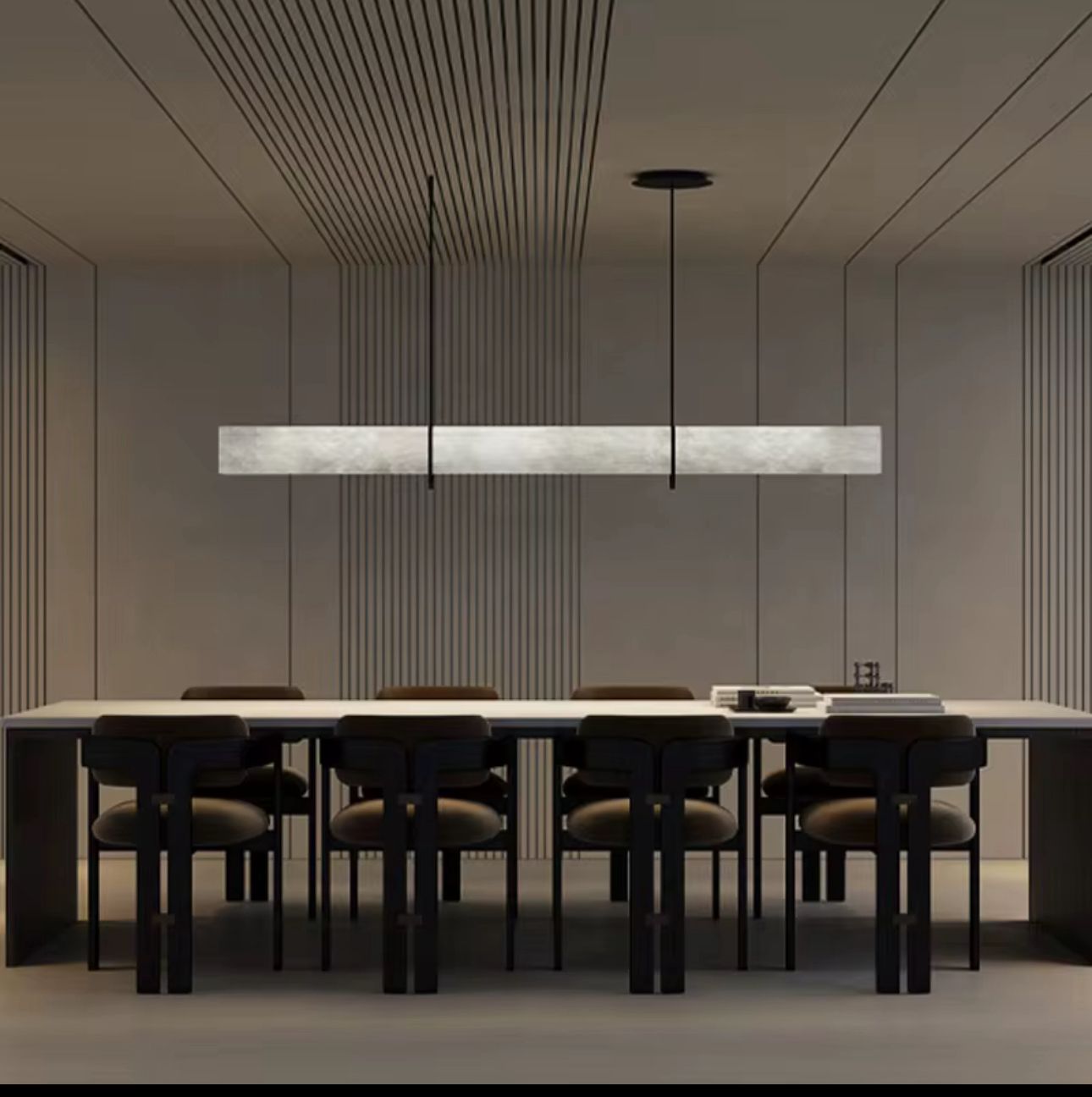 Modern dining room with a long table and chairs, featuring a sleek pendant light.