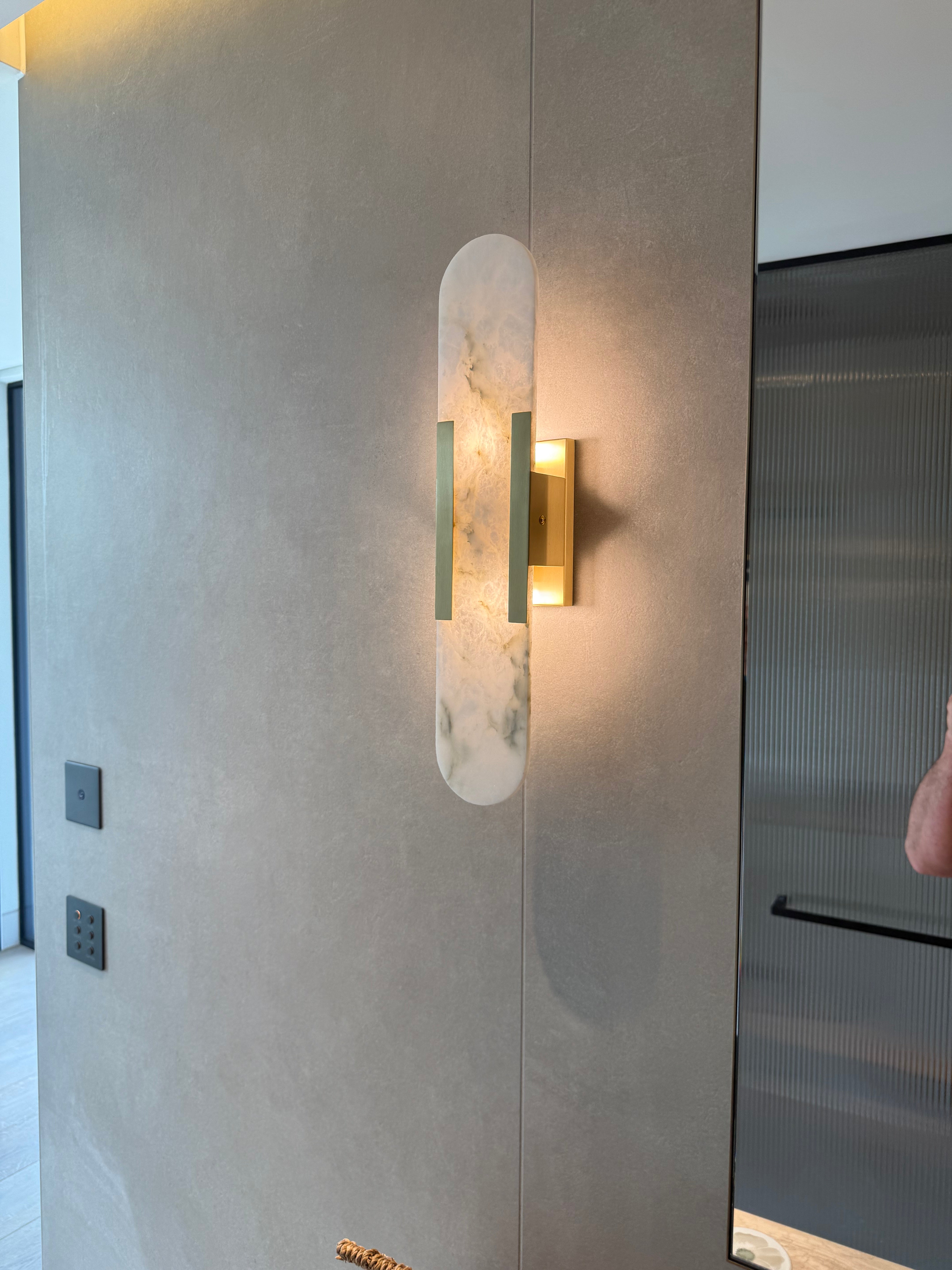 Modern wall sconce with marble-like finish on a gray wall.