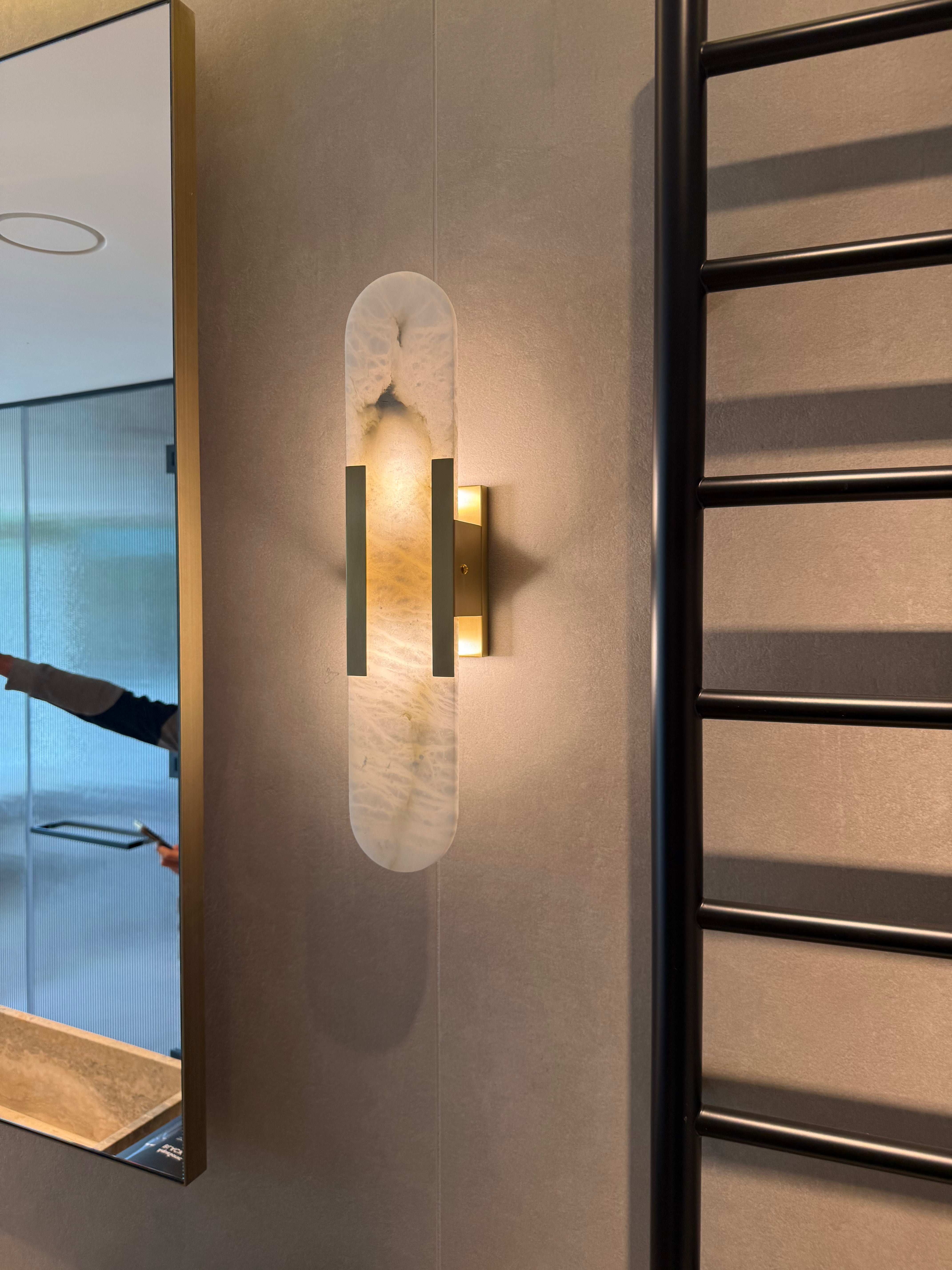 Modern wall sconce with a reflective surface on a neutral wall.