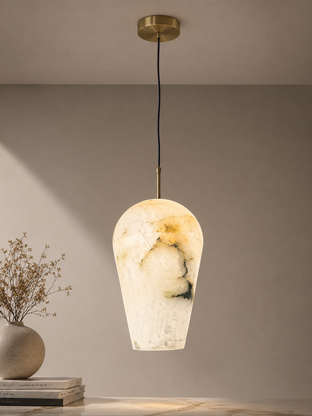 Marble-textured pendant light hanging against a neutral wall with a vase and books on a surface.
