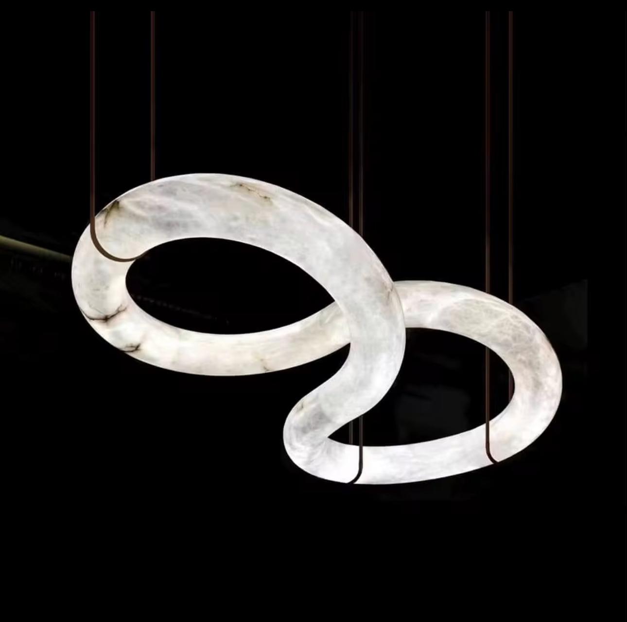 Modern pendant light with two interlocking rings on a black background